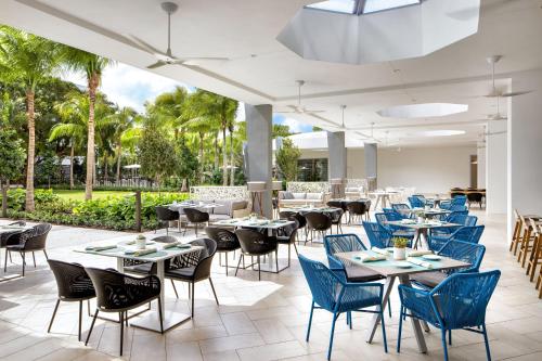 a restaurant with tables and chairs and palm trees at Le Meridien Dania Beach at Fort Lauderdale Airport in Dania Beach