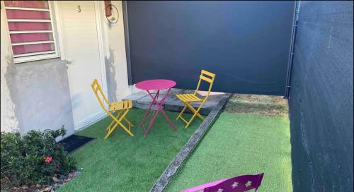a patio with two chairs and a table on grass at Les Terrasses du Musee Didier in Fort-de-France