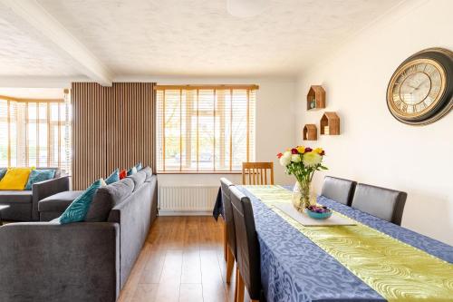 a dining room with a table and chairs and a clock at Beautiful 3 bedroom house with garden + Parking in Oxford