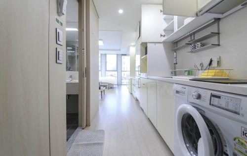 a white kitchen with a washer and dryer in it at The Hide City in Jeju