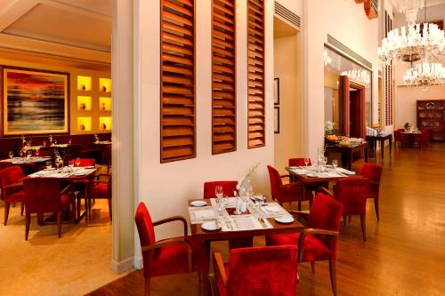 a restaurant with tables and red chairs in a room at Le Meridien Al Khobar in Al Khobar