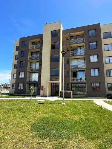 a building with a grass field in front of it at Departamento en Linares in Linares