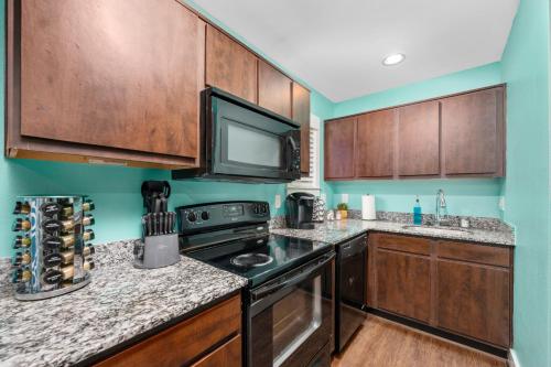 a kitchen with wooden cabinets and a black stove at Chic 1BR Stay with King Bed and Free Park in Houston