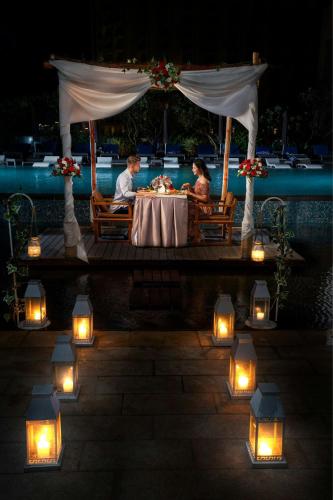 a couple sitting at a table under a gazebo with lights at Sheraton Nha Trang Hotel & Spa in Nha Trang
