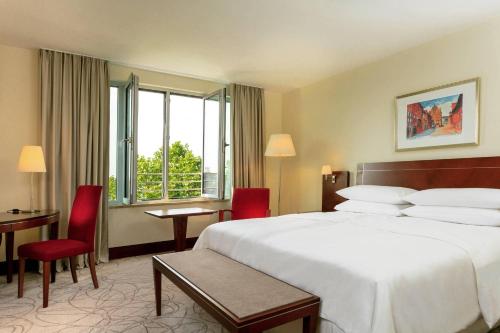 a hotel room with a bed and a table and chairs at Sheraton Carlton Nuernberg in Nürnberg