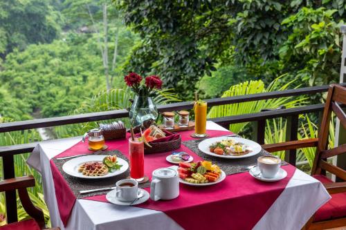 a table with plates of food on a red table cloth at Griya Shanti Villas & Spa in Ubud