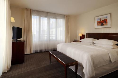 a hotel room with a bed and a flat screen tv at Sheraton Carlton Nuernberg in Nürnberg