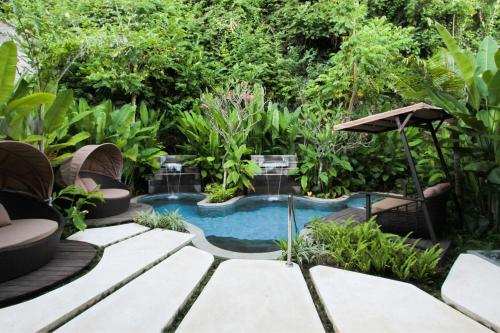 a swimming pool in a garden with trees at The Ritz-Carlton Bali in Nusa Dua