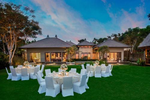 a set of white tables and chairs in front of a house at The Ritz-Carlton Bali in Nusa Dua