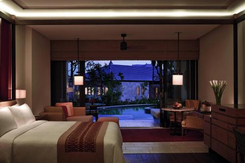 a hotel room with a bed and a swimming pool at The Ritz-Carlton Bali in Nusa Dua