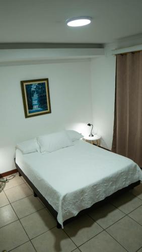 a bedroom with a large white bed in a room at Casa Calas in Alajuela City