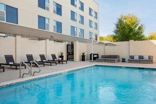 a swimming pool with chairs and a building at The Elmore Hotel, DFW Southlake, a Tribute Portfolio Hotel in Southlake