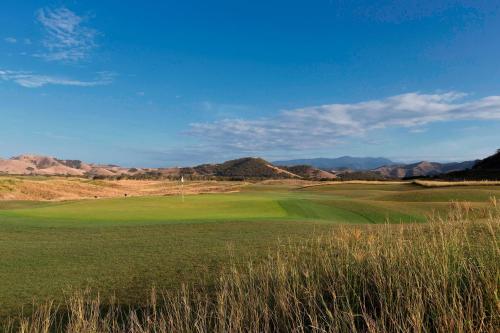 a view of a golf course with mountains in the background at Sheraton New Caledonia Deva Spa & Golf Resort in Bourail