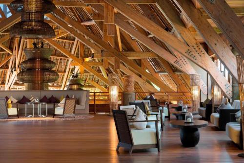 a large lobby with wooden ceilings and chairs and tables at Sheraton New Caledonia Deva Spa & Golf Resort in Bourail