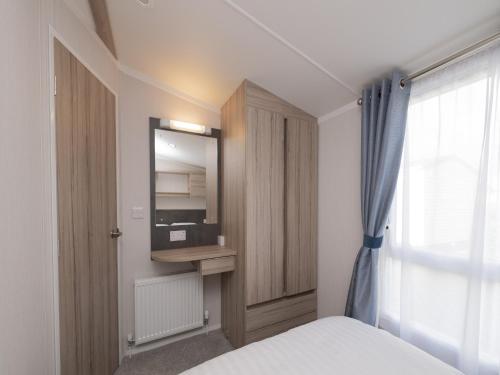 a bedroom with a bed and a cabinet and a window at Sunking Caravan by Belvilla in Looe