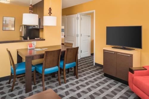 a dining room with a table and a flat screen tv at TownePlace Suites by Marriott New Hartford in New Hartford