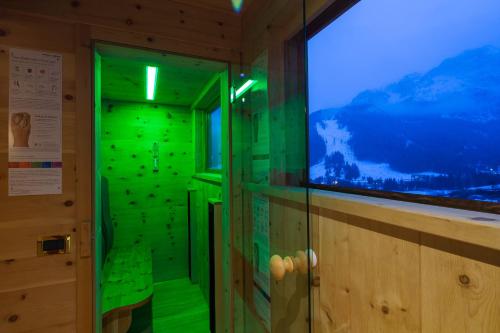 a green shower in a room with a window at Hotel Sassongher in Corvara in Badia