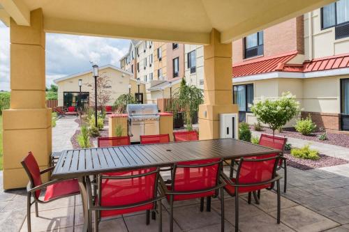a patio with a black table and red chairs at TownePlace Suites by Marriott New Hartford in New Hartford
