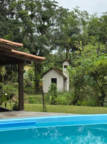 a house in the background with a swimming pool in the foreground at Hotel pousada Araquari in Araquari