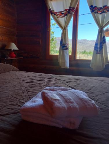 a bed with a towel on it with a window at Cabañas Angualasto in Uspallata
