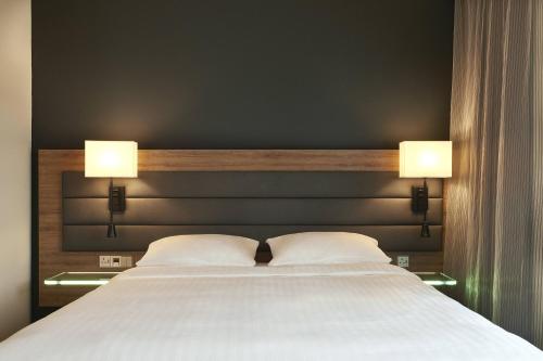a bedroom with a large bed with two lamps on it at Moxy York in York