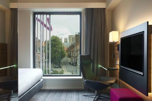 a hotel room with a bed and a large window at Moxy York in York