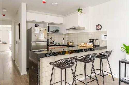 a kitchen with three bar stools and a refrigerator at Cómodo y silencioso Apartamento 1BR en Barranco in Lima