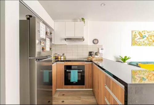 a kitchen with a stainless steel refrigerator and wooden cabinets at Cómodo y silencioso Apartamento 1BR en Barranco in Lima