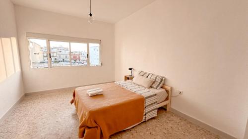 a bedroom with a bed with an orange blanket and a window at Asthet Sevilla in Mairena del Aljarafe