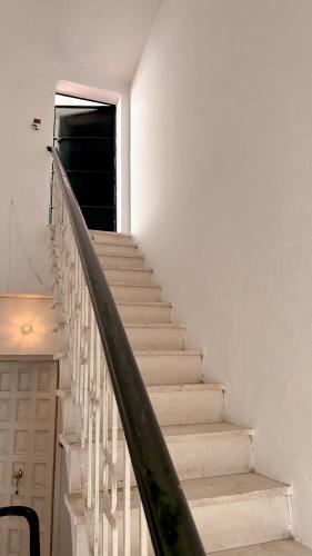 a staircase in a white house with a black door at Asthet Sevilla in Mairena del Aljarafe