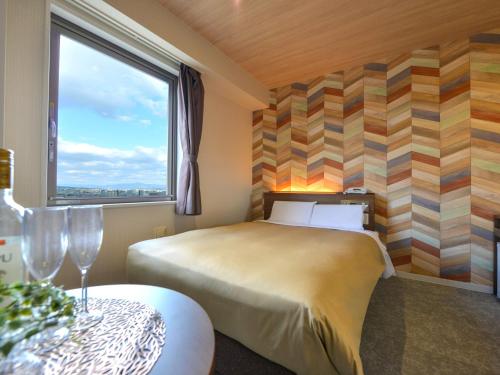 a bedroom with a bed and a window and a table at Hotel New Gaea Nishi Kumamoto Ekimae in Kumamoto