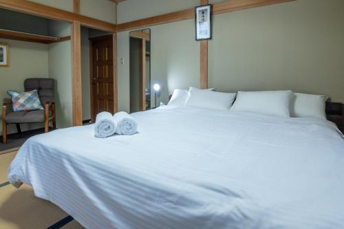 a bedroom with a large white bed with towels on it at Welcome Nozawa in Nozawa Onsen