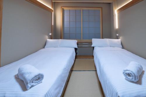 two beds in a room with towels on them at Welcome Nozawa in Nozawa Onsen