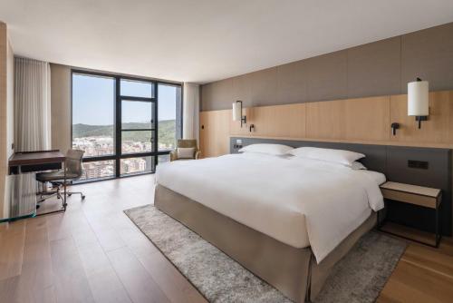 a bedroom with a large white bed and a piano at Taipei Marriott Hotel in Taipei