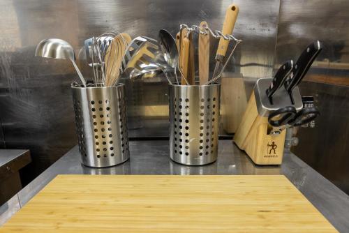 three metal containers filled with utensils on a counter at Welcome Nozawa in Nozawa Onsen