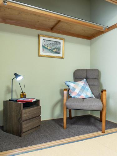 a chair and a table with a lamp and a pillow at Welcome Nozawa in Nozawa Onsen