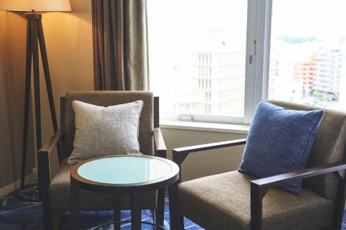 a room with two chairs and a table and a window at Rihga Royal Gran Okinawa in Naha