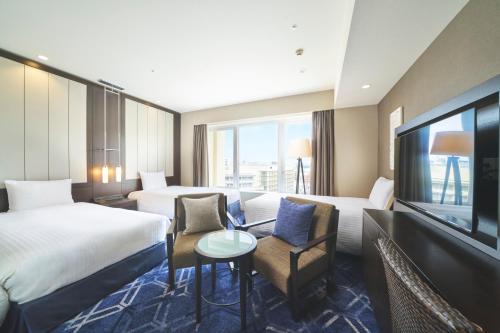 a hotel room with two beds and a flat screen tv at Rihga Royal Gran Okinawa in Naha