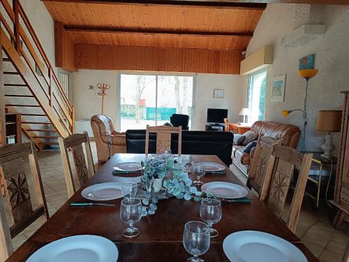 Una mesa de comedor con platos y vasos encima. en Maison familiale près plage St Brevin, animaux admis, parking privé - FR-1-364-40, en Saint-Brevin-les-Pins