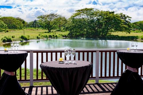 two tables with wine glasses and a view of a lake at Sheraton Samoa Beach Resort in Mulifanua