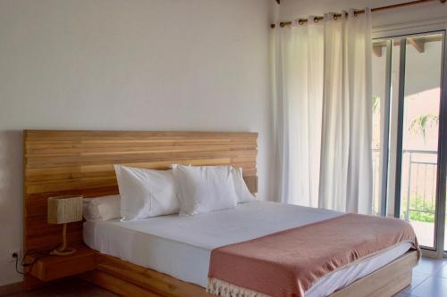 a bedroom with a bed with a wooden headboard and a window at Villa Camélia in Oyster Pond