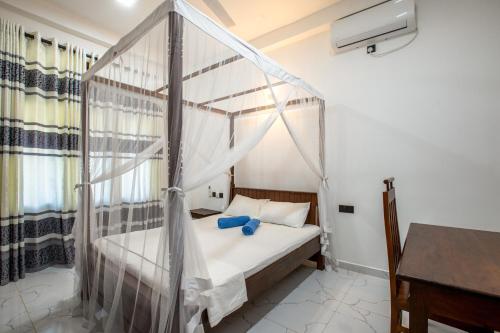 a bedroom with a canopy bed and a desk at Blueray Villa in Unawatuna
