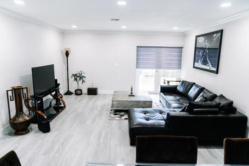 a living room with a black leather couch and a television at Welcome to 305 Rentals in Miami Gardens
