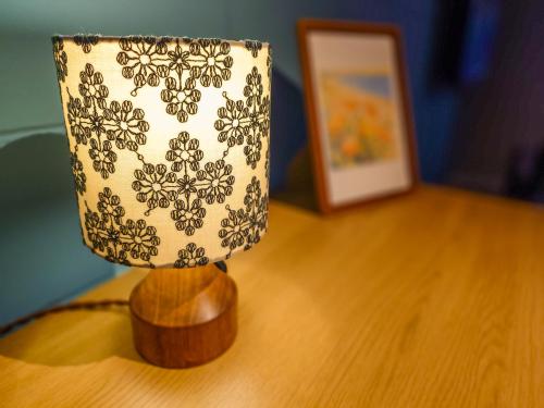 a lamp on top of a wooden table next to a picture at サンメール座間味アネックス in Zamami