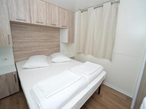 a white bed with two pillows in a room at Mobile Homes in Camp Kovacine, Cres, with long pebble beach in Cres