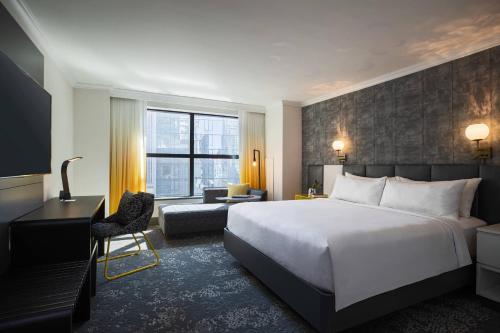 um quarto de hotel com uma cama, uma secretária e uma cadeira em Renaissance New York Times Square by Marriott em Nova Iorque