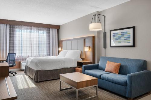 a hotel room with a bed and a blue couch at Holiday Inn Express Hotel & Suites Coralville by IHG in Coralville