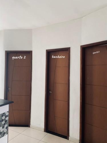 a row of three brown doors in a room at Chalé Di vino in Porto Seguro