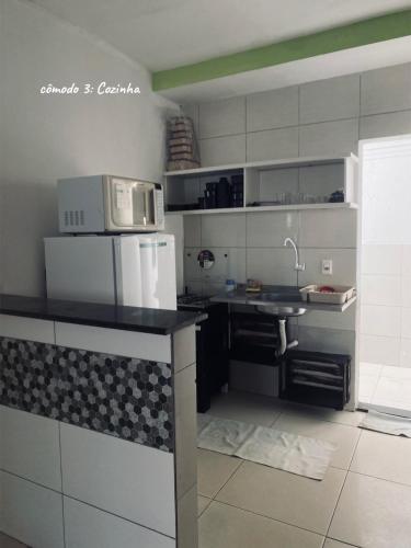 a kitchen with a sink and a microwave at Chalé Di vino in Porto Seguro