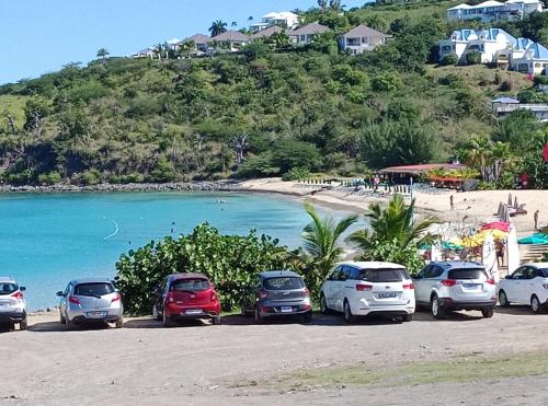 a group of cars parked on the beach at Logement Coquelicot in Friar's Bay